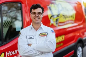 Dan, a Sarasota Mister Sparky electrician, standing confidently in front of a red service van.