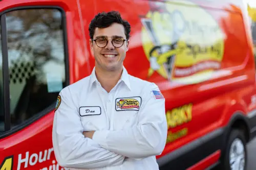 Dan, a Sarasota Mister Sparky electrician, standing confidently in front of a red service van.