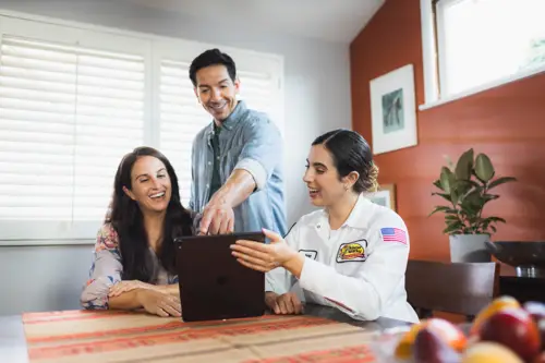 Jane, a Sarasota Mister Sparky electrician, assisting homeowners with electrical solutions using a tablet at their dining table. Is An Electrical Inspection Worth It?