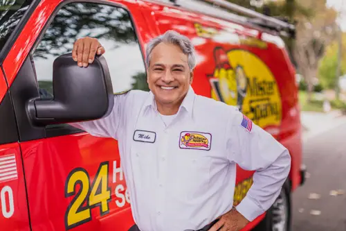 Mike, a Sarasota Mister Sparky electrician, standing confidently next to a red service van.