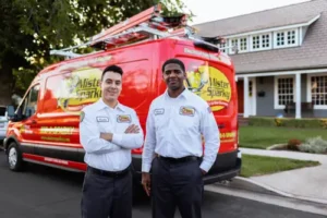 Mister Sparky Sarasota electricians Emilio and a team member standing in front of a red service van in a residential neighborhood.