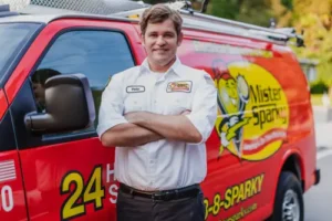 Pete, a Sarasota Mister Sparky electrician, standing confidently in front of a red service van.