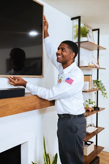 Mister Sparky Sarasota electrician installing a TV for a homeowner in a living room.