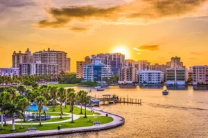 The Sarasota skyline at sunset, featuring buildings, palm trees, and waterfront views.